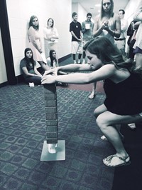 A student intently focuses on stacking her bricks