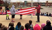 Paul McNeal and Safety Patrol members properly fold a USA flag
