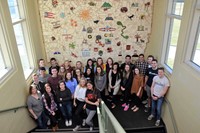 Graduating seniors from each high school stand in front of the mural they helped create while students at Fouse Elementary School.