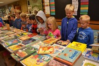 First grade students at Mark Twain Elementary School ponder their choice of books that are placed on a very large table 
