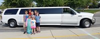 Five students, a secretary and principal stand in front of a limo before taking a ride to lunch.