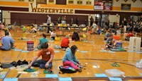 Dozens of students building with Legos on the gym floor at WNHS.