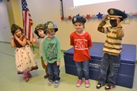 Five pre-school students try on different military headgear.