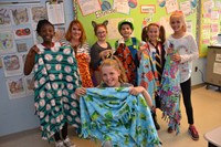 Six students and a parents hold blankets they made