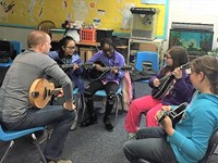 Mick Broderick giving mandolin lessons to youngsters