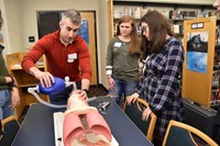 Physician Assistant Scott Naples intubates a mannequin as Westerville Central pupils Kaycee Johnston and Mackenzie Little observe.