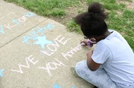 Annehurst Elementary student draws a message on the playground during the school's 50th birthday party